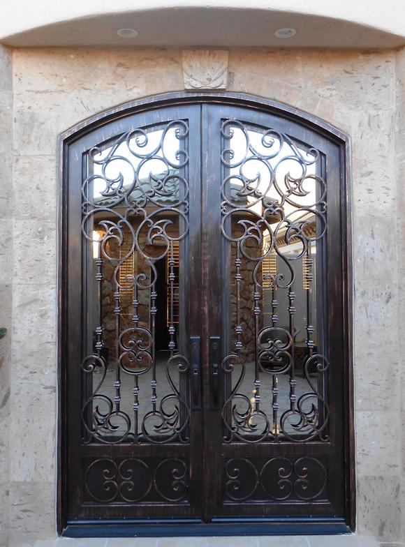 Ornate iron scrollwork double door in travertine surround